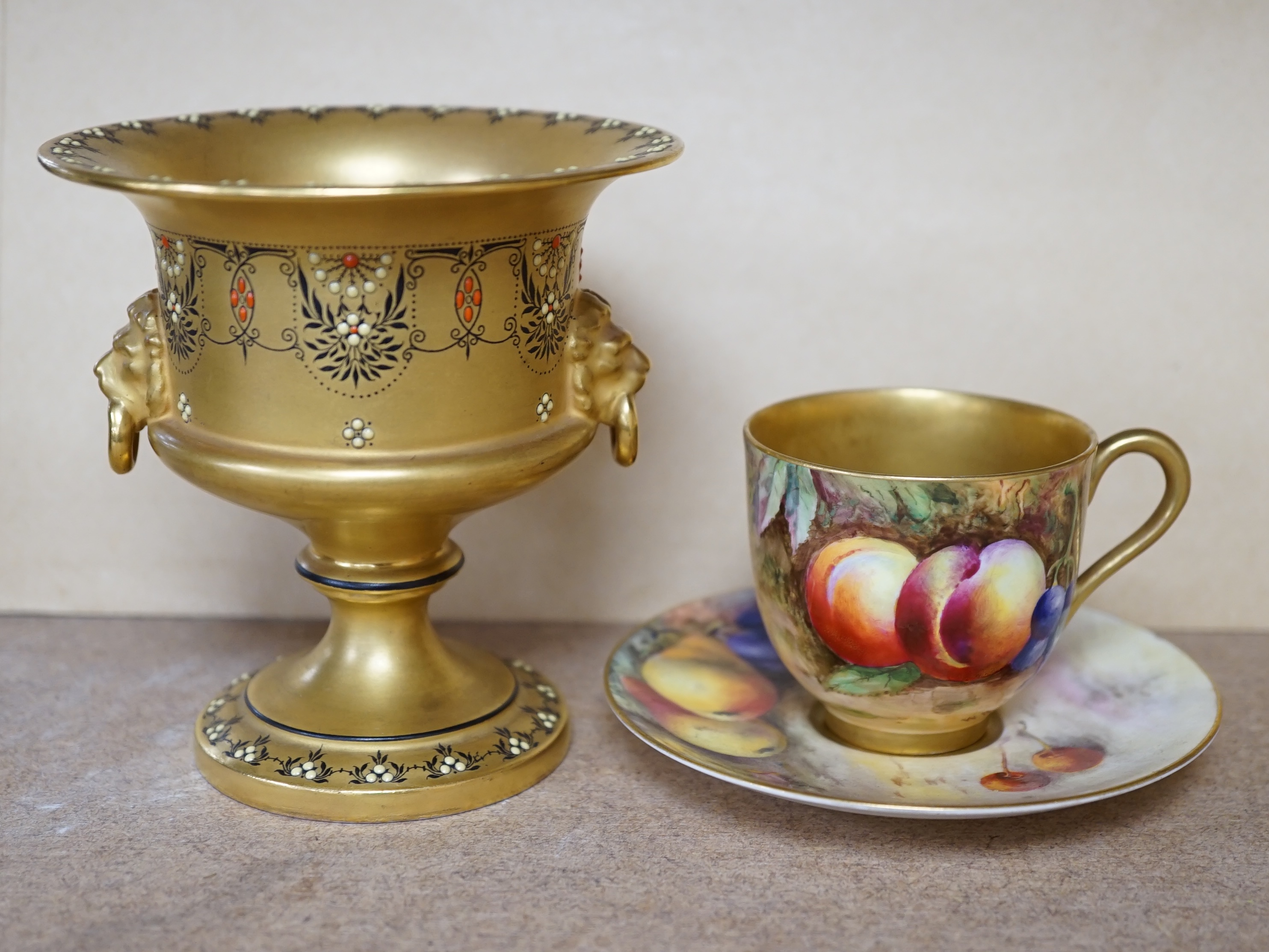 A Royal Worcester miniature fruit painted cup and saucer, Hale and Everett, and an unusual gilded campana vase, 10cm high. Condition - saucer cracked, otherwise good